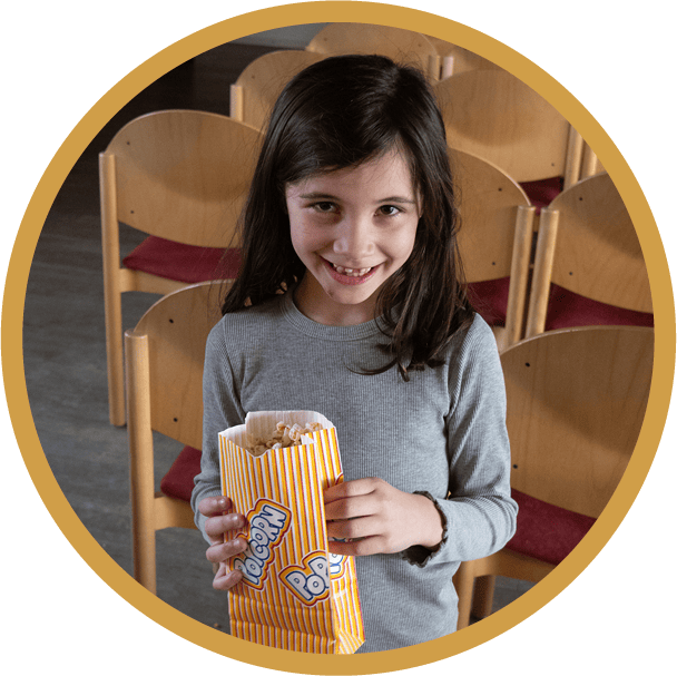Glückliches Mädchen halt eine Popcorntüte in der Hand.