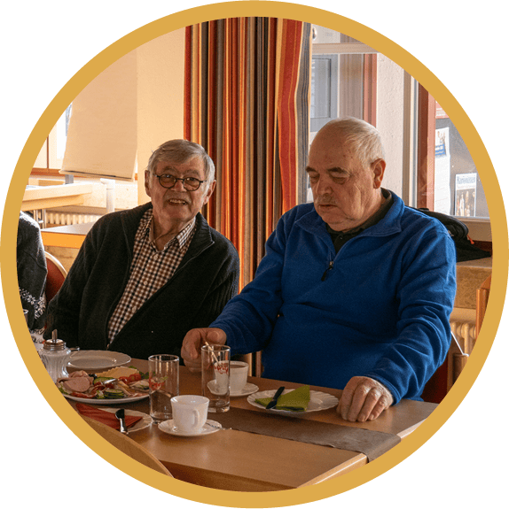 Zwei Senioren sitzen am Tisch beim Frühstücken.